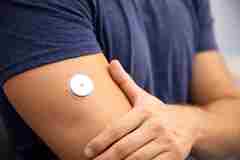 A man using a flash glucose sensor on his arm. 