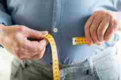 A person with measuring tape around stomach. 